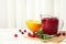Tasty cranberry sauce in glass pitcher with rosemary and citrus fruit on table.