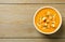 Tasty creamy pumpkin soup with croutons and seeds in bowl on wooden table, top view. Space for text