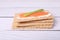 Tasty crispbreads with salmon, cream cheese and green onion on white wooden table, closeup