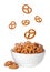 Tasty crispy pretzel crackers falling into bowl on background