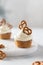 Tasty cupcakes with cream cheese decorated with brezel on white marble tray on white background. Party, happy birthday, pastry,