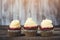 Tasty cupcakes with cream cheese frosting. Homemade cupcakes on rustic wooden board. Cupcakes for party. Three delicious muffins