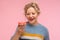 Tasty dessert. Portrait of woman with short curly hair in sweater holding doughnut, looking with desire at donut