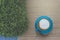 Tasty drinking, blue cup of cappuccino coffee, flower pattern milk forth on vintage wooden table and green bush, top view photo