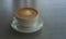 Tasty drinking, a cup of capuccino coffee decorated with heart pattern on brown milk froth in white ceramic cup on gray table