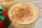 Tasty eggnog with cinnamon on white wooden table, closeup