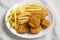 Tasty Fastfood: Chicken Nuggets and French Fries on a plate on cloth, low angle view. Close-up