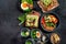 Tasty food with avocado toast, vegetables, eggs on dark background. Helthy breakfast concept