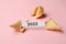 Tasty fortune cookies and paper with number 2023 on pink background