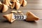 Tasty fortune cookies and paper with number 2023 on wooden table