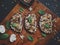 Tasty fresh bruschetta with mushrooms, spinach, garlic, cream cheese and pine nuts, on a wooden board, on a dark background.