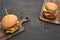Tasty fresh cheeseburgers on wooden boards on black table