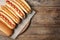 Tasty fresh hot dogs on wooden table, top view.