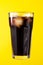 Tasty fresh iced cold black coffee with ice on yellow vivid back