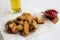 Tasty fried chicken wings with sauce, cold beer on a white wooden background