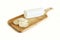 A tasty goat cheese roll atop a wooden cutting board over white background