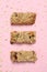 Tasty granola bars on pink background, flat lay