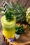 Tasty green smoothie full of vitamins and minerals decorated with slices of citrus fruit and a pineapple in the background