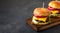 Tasty grilled home made burger with beef, tomato, cheese, cucumber and lettuce on a dark stone background with copy space