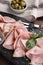 Tasty ham with basil, peppercorns and carving fork on table, closeup