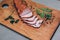 Tasty ham lying on the wooden panel plank. Meat with green leaves spinach. Food photo with pepper spices
