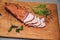 Tasty ham lying on the wooden panel plank. Meat with green leaves spinach. Food photo with pepper spices