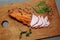 Tasty ham lying on the wooden panel plank. Meat with green leaves spinach. Food photo with pepper spices