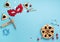 Tasty hamantaschen cookies, red carnival mask, noisemaker, sweet candies and party decor on blue background.