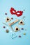 Tasty hamantaschen cookies, red carnival mask, noisemaker, sweet candies and party decor on blue background.