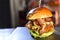 Tasty handmade hamburger sandwich with onion tomato lettuce and bread served on top of a stone on black background