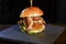 Tasty handmade hamburger sandwich with onion tomato lettuce and bread served on top of a stone on black background