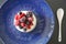 Tasty and healthy dessert made from creamy base on the blue plate, with mix of the berries on the top
