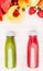 Tasty and healthy summer beverages in bottles with fruits and berries ingredient. Red and green smoothie or juice on white wooden