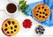 Tasty homemade berry pies in a round ceramic form, a cup of tea on a white wooden background