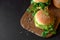Tasty homemade burgers with lettuce, ketchup, cheese and chicken on brown wooden background. Copy space