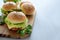 Tasty homemade burgers with lettuce, ketchup, cheese and chicken on gray wooden background. Copy space