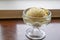 The tasty homemade cool vanilla ice cream scoop in glass cup on wood table.