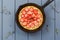 Tasty homemade pie with mascarpone filling and fresh strawberries in cast iron skillet with dried thyme