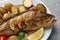 Tasty homemade roasted perch with garnish on grey table, closeup. River fish