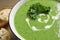 Tasty kale soup with cream on wooden table