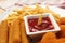 Tasty ketchup, fries and cheese sticks on plate