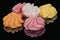 Tasty Meringues in different colors, isolated on black background