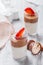 Tasty mousse dessert with chocolate, strawberry and praline in a glass on light background close up. Delicious dessert