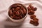 Tasty pecan nuts with bowl on beige cloth, closeup