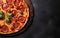 Tasty pepperoni pizza on black concrete background, pizza with basil and tomatoes on wooden board, copy space, top above view