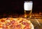 Tasty pepperoni pizza on wooden table near a glass of beer