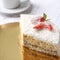 Tasty piece of sweet strawberry cake with red berries on cup of coffee americano, white background. Homemade delicious