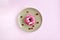 Tasty pink glazed doughnut and cranberry on beige round plate on pink background. Top view of delicious donut. Close-up.