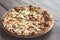 Tasty pizza close up on plate and wooden table. Pizza with onion, tomatoes, cheese, meat and pepper. Toned image