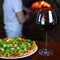 Tasty pizza and glass with red wine in a traditional restaurant with a fire stone stove.